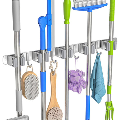 Wall broom and mop holder: rail holding five mops and brooms, with brushes and a towel on the hooks.