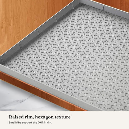 Under-sink leak mat: close-up of the raised rim, support ribs and hexagon texture.